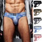 Model wearing blue mosaic-print men's briefs with brand logo on the waistband; body visible from chest to mid-thighs.