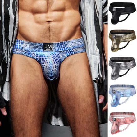 Model wearing blue mosaic-print men's briefs with brand logo on the waistband; body visible from chest to mid-thighs.