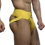 Close-up of a man wearing a bright yellow jockstrap with a wide waistband and side support straps.