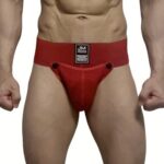 Male torso wearing red jockstrap underwear with black tag at the waistband; close-up of the front view.