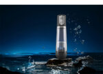 Portable water flosser standing upright on a rock in the ocean at night, with waves splashing around.