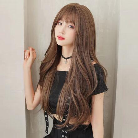 Waist-up portrait of a young woman with long brown hair, wearing a black off-shoulder top and a black star pendant choker, posed against a neutral background.