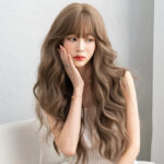 Young woman with long, wavy light brown hair rests her chin on her hand, looking to the side in a neutral pose.