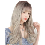 Woman with long, wavy ash-gray hair wearing a blue gingham off-shoulder top and a star pendant necklace, looking down thoughtfully.