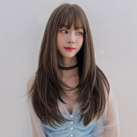 Young woman with long brown hair and bangs, wearing a black lace choker and light blue sheer top, facing slightly to the left with a soft smile.