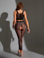 Woman seen from behind in a black lace bodysuit and sheer patterned tights, standing against a gray backdrop with long hair flowing down, wearing clear-heeled sandals