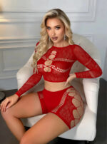 Woman with long blonde hair in a red lattice bodysuit sits on a white chair, posing for a photo shoot.